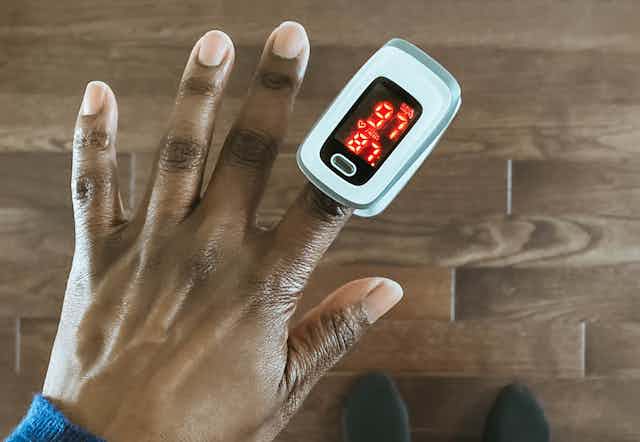 A woman uses a pulse oximeter.