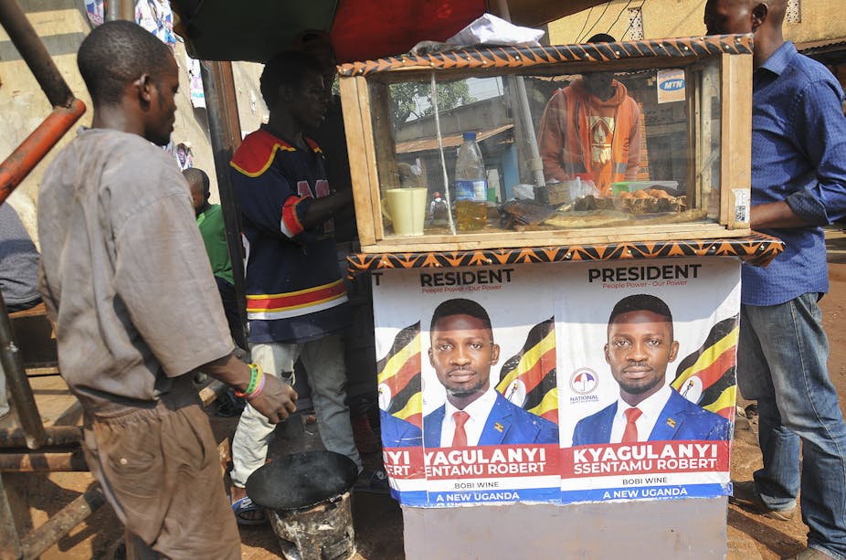 A Ugandan man looks at election posters promoting opposiiton candidate Bobby Wine.