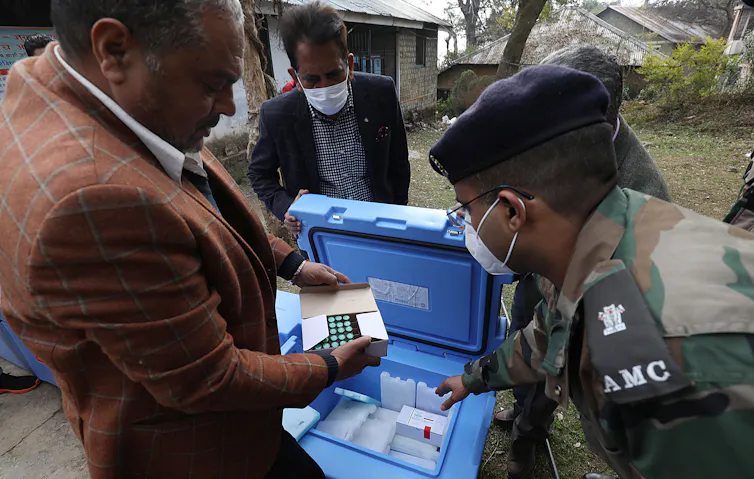 A man and soldiers inspect a delivery of vaccines produced by the Serum Institute of India