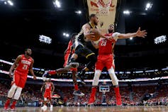 A basketball player passes the ball to another player.