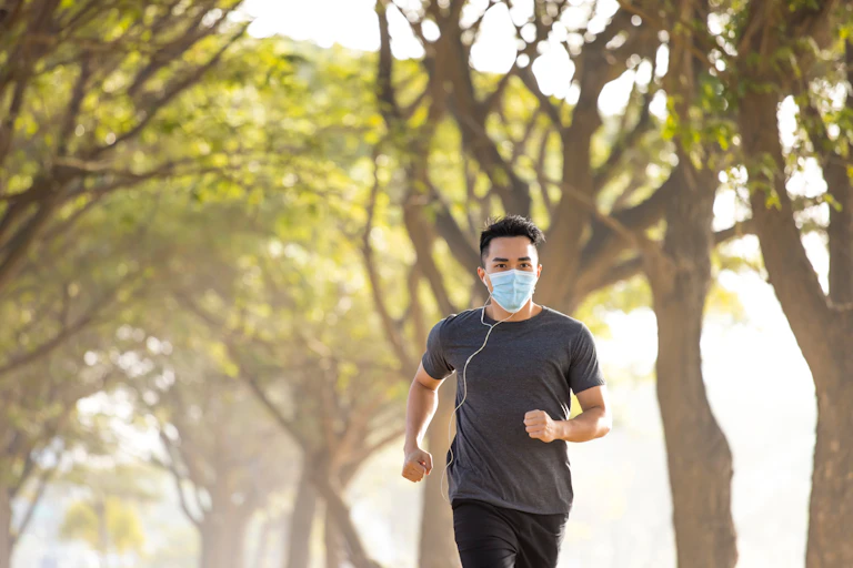 Man running in the park, wearing a mask.