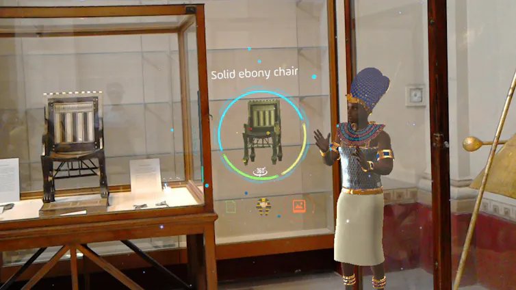 An animated pharoh shows off an ancient chair in a museum