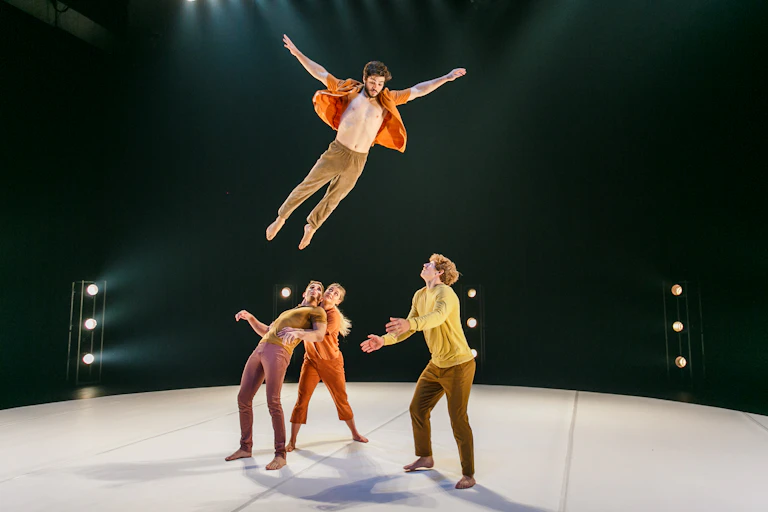 A man flies through the air, arms outstretched, heading towards a man's waiting arms.