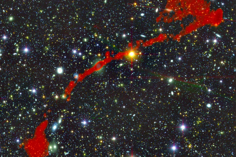Dark background with many points of light of different sizes and a long, thin red shape