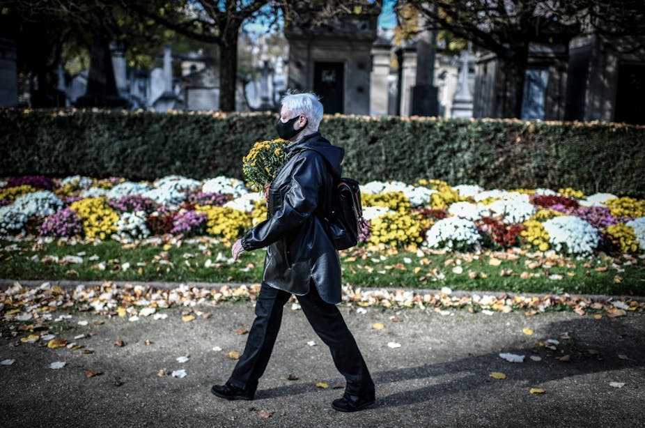 Une femme portant un masque apporte des fleurs au cimetière Montparnasse