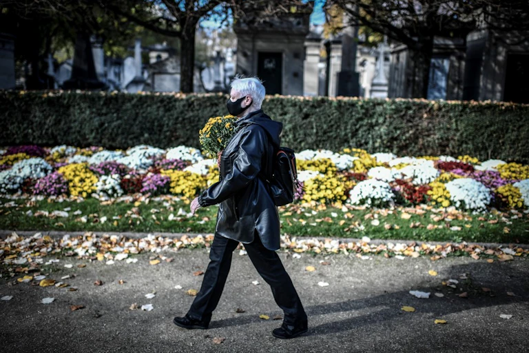 Une femme portant un masque apporte des fleurs au cimetière Montparnasse
