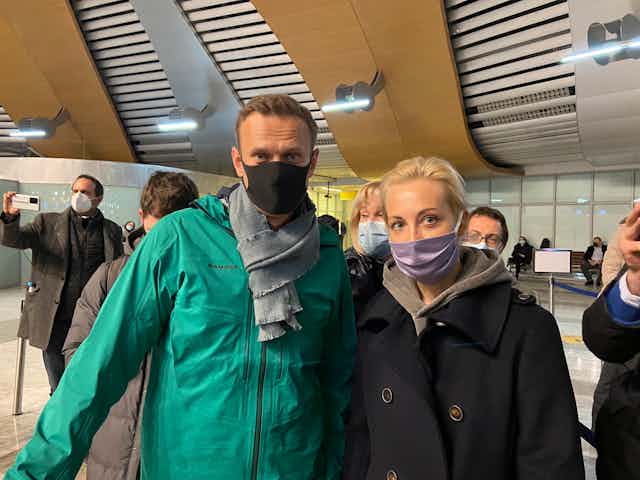 Middle-aged man and woman posing in COVID masks for a photograph at Moscow's Sheremetyevo airport.