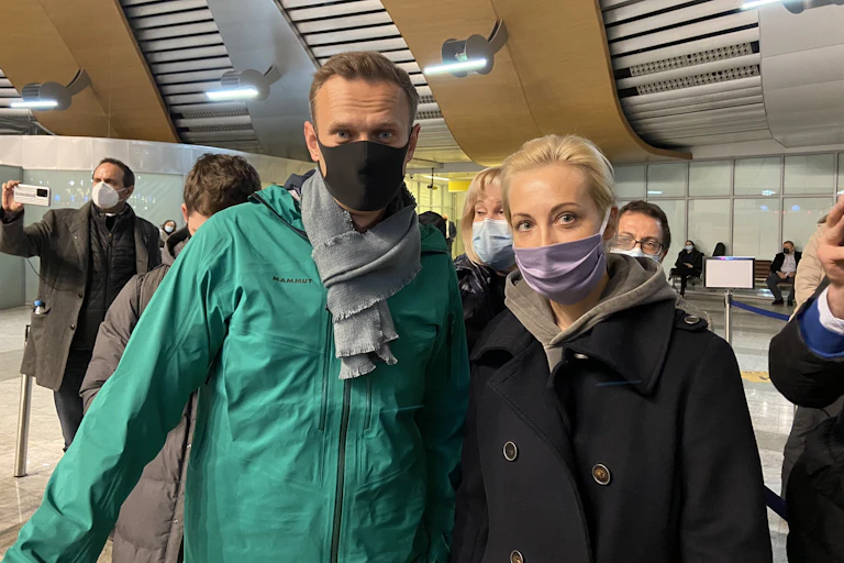 Middle-aged man and woman posing in COVID masks for a photograph at Moscow's Sheremetyevo airport.