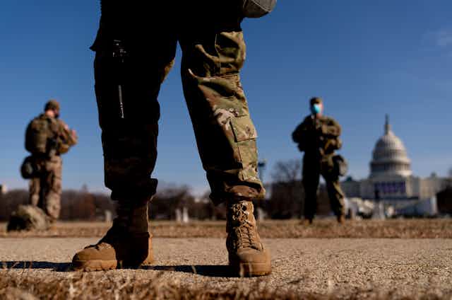 National Guard soldiers are seen with the U.S. Capitol in the background on a sunny day.