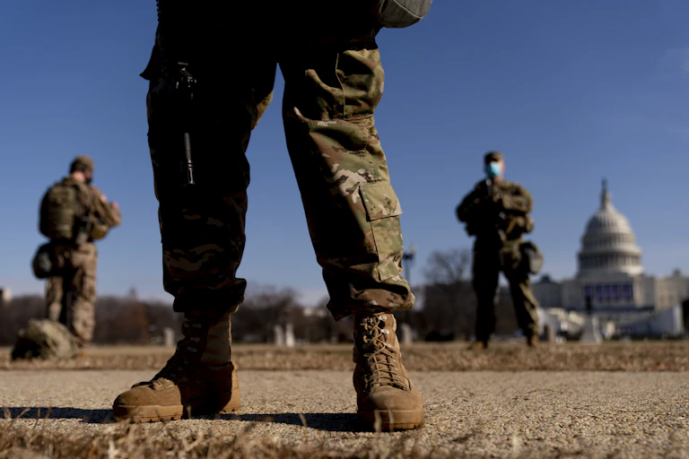 National Guard soldiers are seen with the U.S. Capitol in the background on a sunny day.