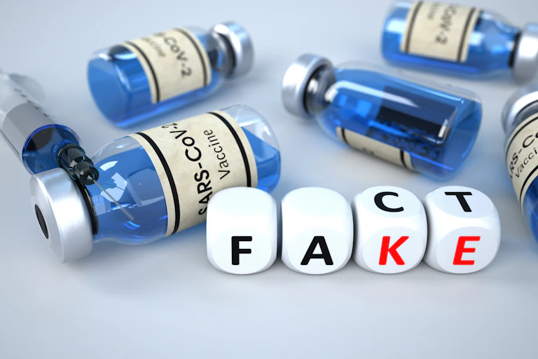Vaccnie bottles on their sides with 'fact' and 'fake' spelt in dice