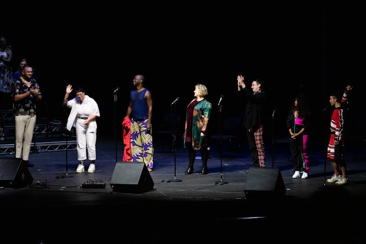 Singers stand on stage.