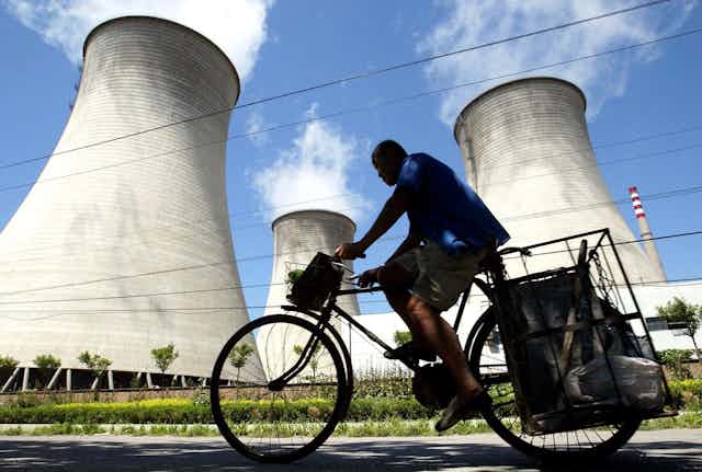 Man rides bike past coal plant