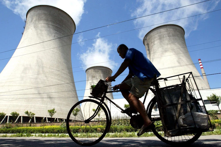 Man rides bike past coal plant