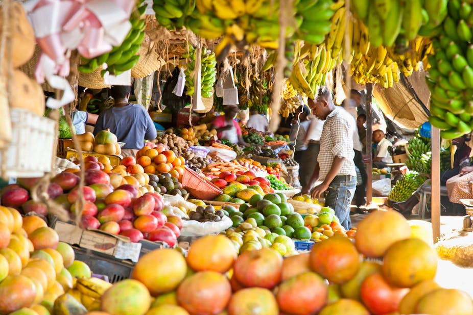 Man standing at a market looking at fresh fruit.