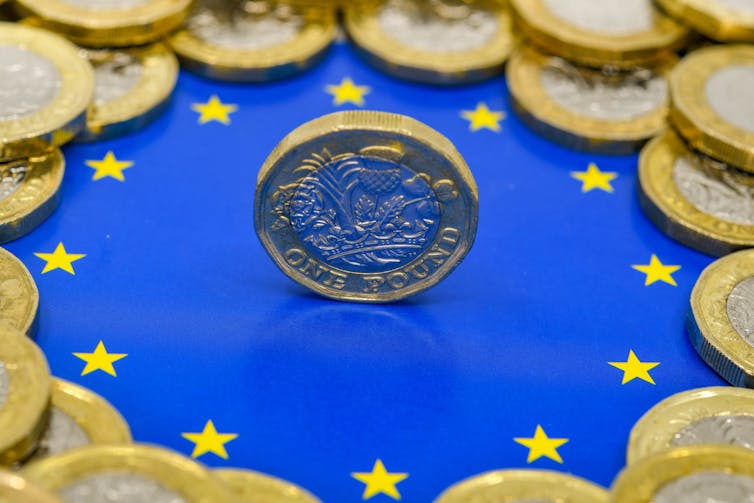 Close up view of British currency GBP - One Pound coin balancing on its edge in the centre of the logo of the European Union.