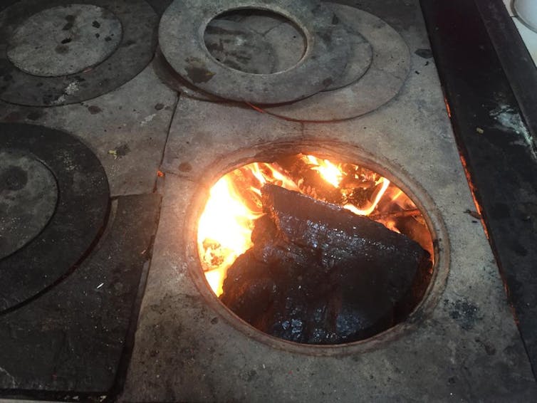 A lit stove filled with a chunk of wood.