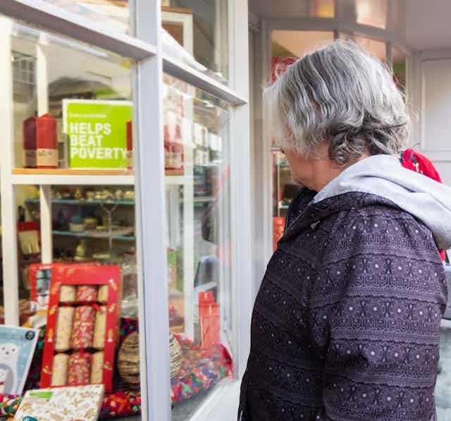 Older woman with in purple jacket looking in charity shop window