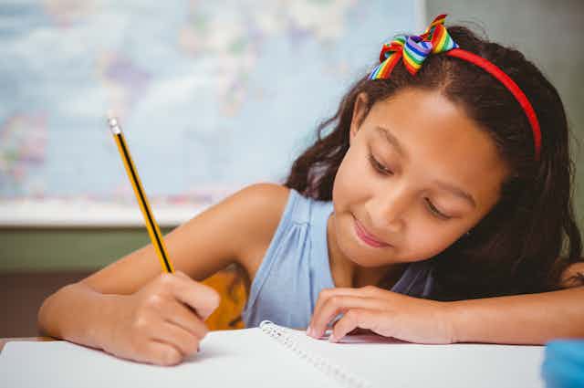 Girl writing in notebook with pencil