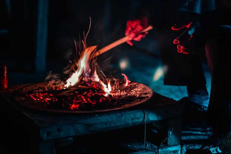 A man stokes a brazier filled with firewood.