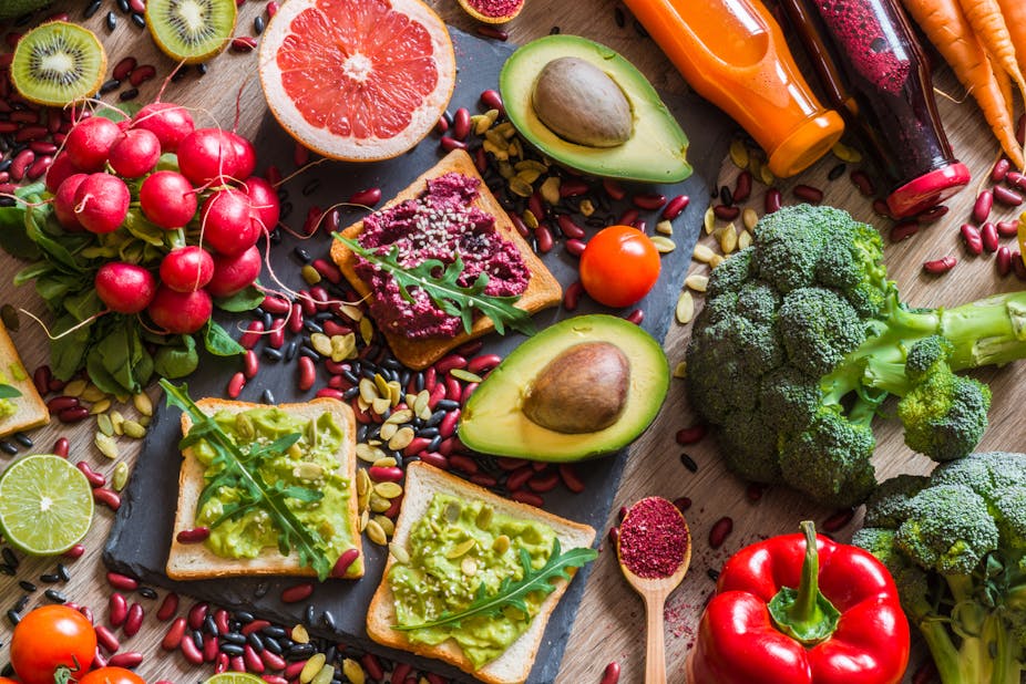 Vegan foods, including avocadoo on bread, grapefruit, broccoli, and peppers.