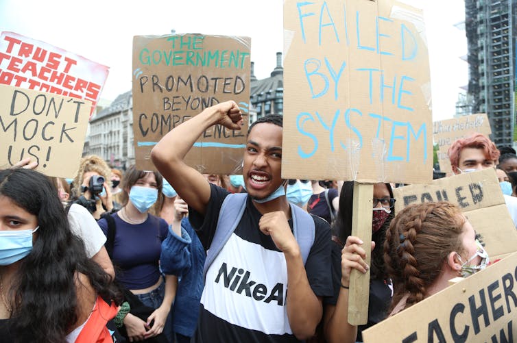 Young people with protest signs, some wearing masks