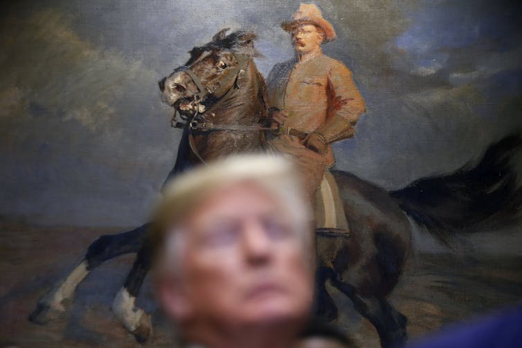 Donald Trump stands in front of a painting of former President Teddy Roosevelt in the White House.
