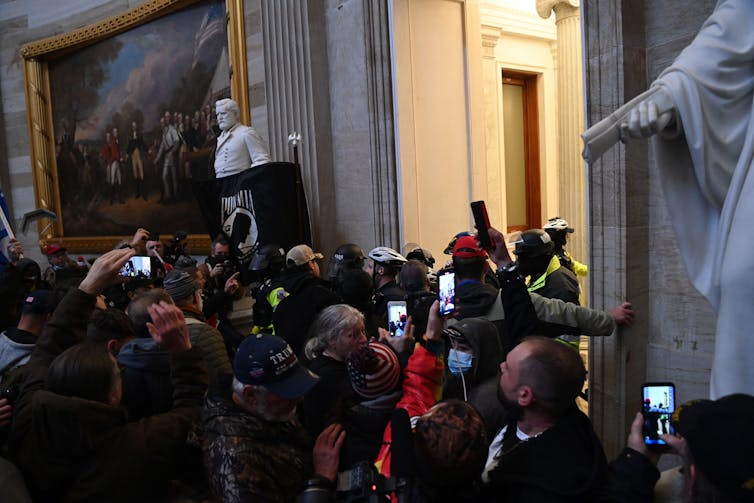 People crowded in the U.S. Capitol building rotunda using cell phones