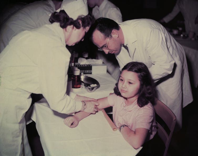 Dr Jonas Salk and a nurse administering a polio vaccine to a girl