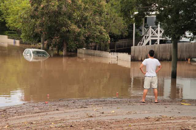 A man looks at floodwaters.