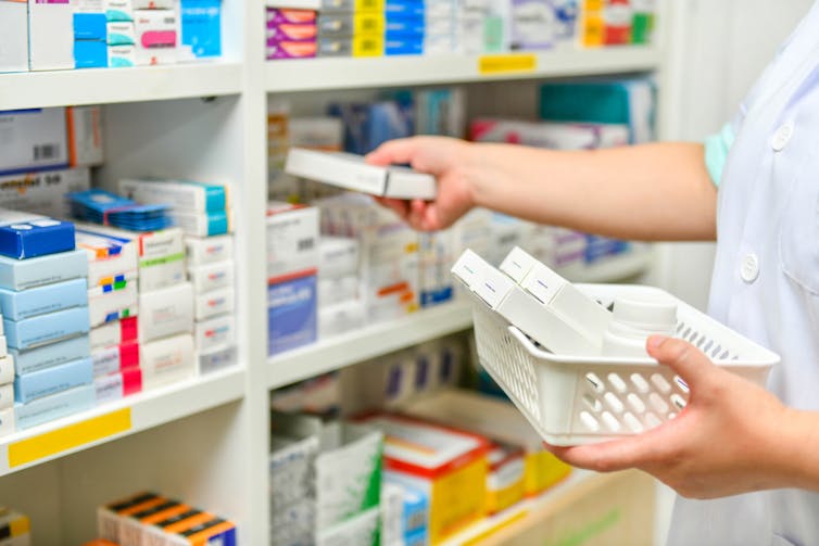 Pharmacist taking medicine off shelf