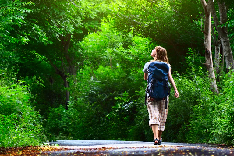 A woman in a backpack walking through a forest