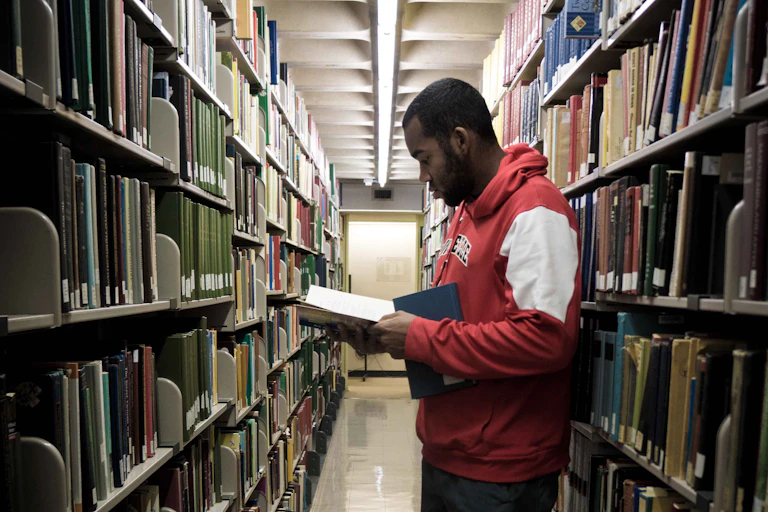 Man stands between two tall shelves of books