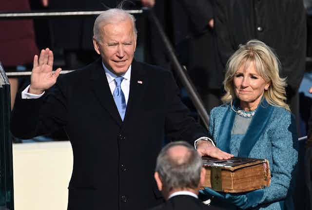 Biden takes the presidential oath of office, his hand on a Bible.