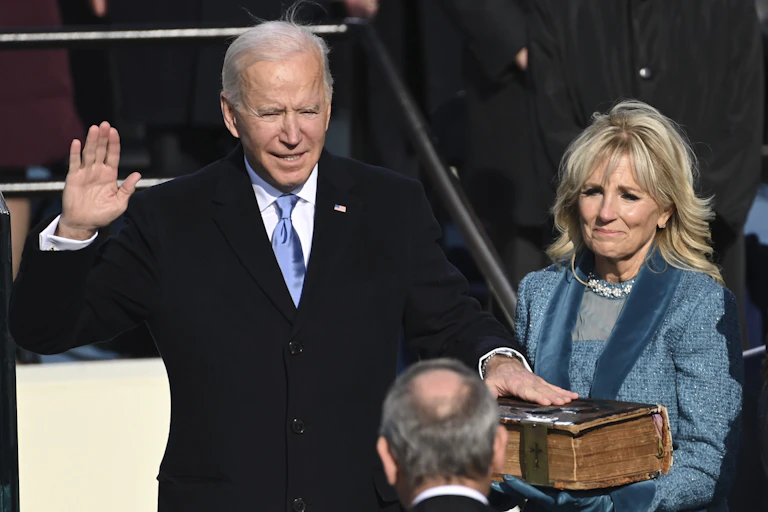 Biden takes the presidential oath of office, his hand on a Bible.