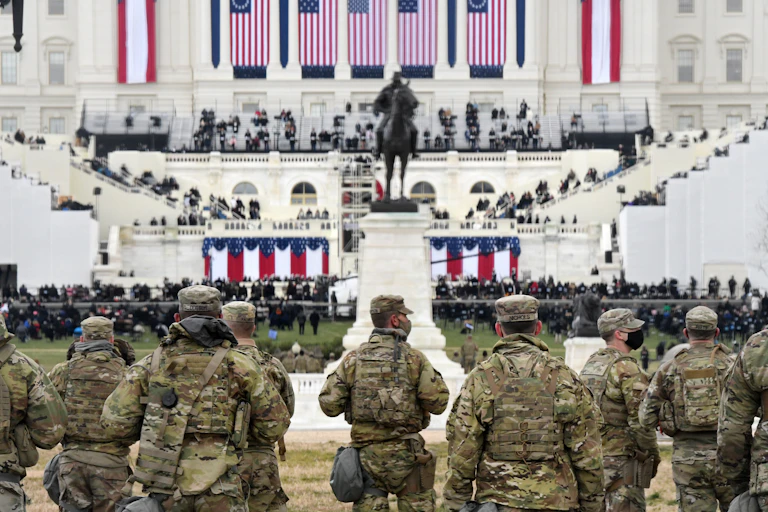 Members of the National Guard gather near the U.S. Capitol, with Biden's inaugural preparations visible in background