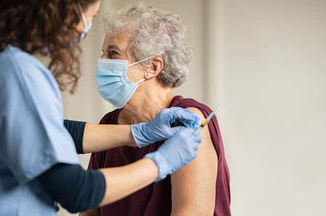 Older woman getting a vaccine. 