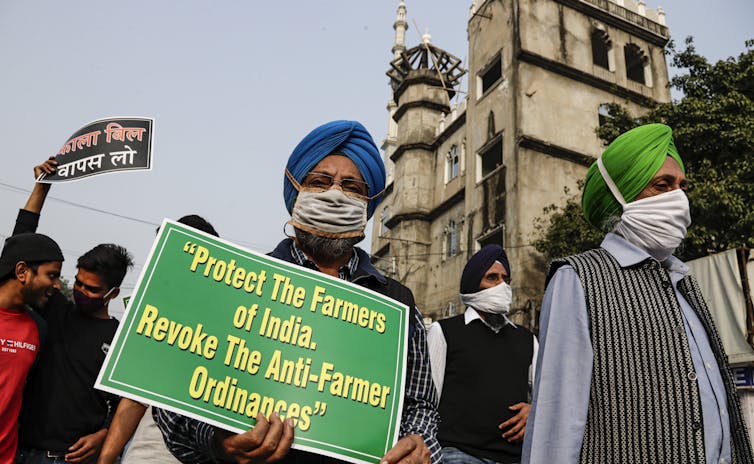 A protester hold a sign that reads: protect the farmers of India, revoke the anti-farmer ordinances.