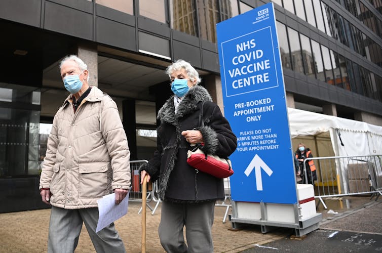 A UK couple leave a COVID vaccine centre in London.