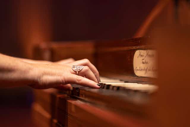 Hands play antique piano keys