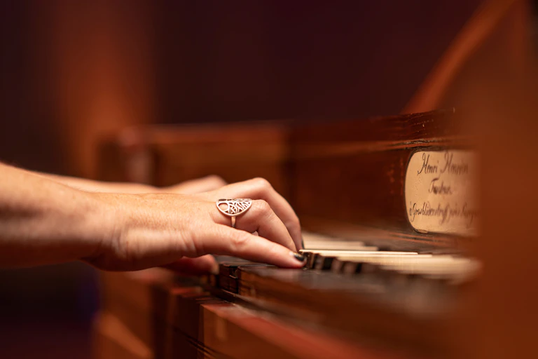 Hands play antique piano keys