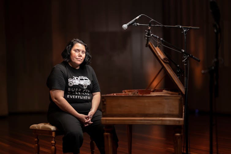 Woman onstage with piano and microphone.