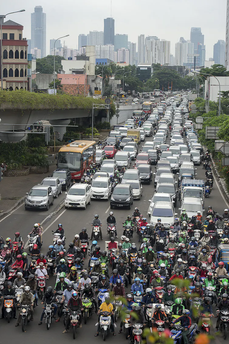 Ratusan mobil dan motor berhenti di depan lampu merah.