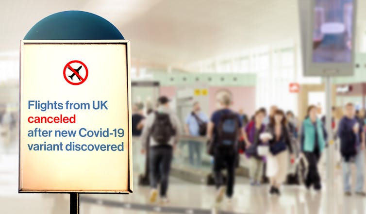 A sign at an airport saying flights from UK cancelled after new COVID-19 variant discovered,