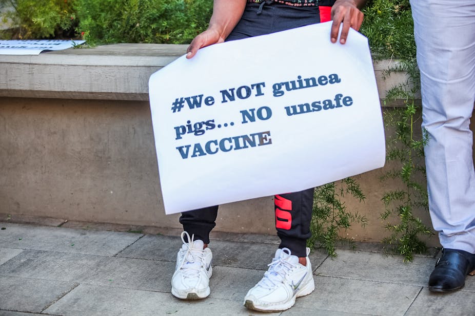 Protesters holding up signs against COVID-19 vaccine trials in Africa 