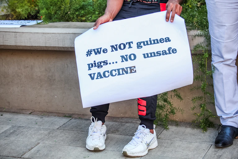 Protesters holding up signs against COVID-19 vaccine trials in Africa