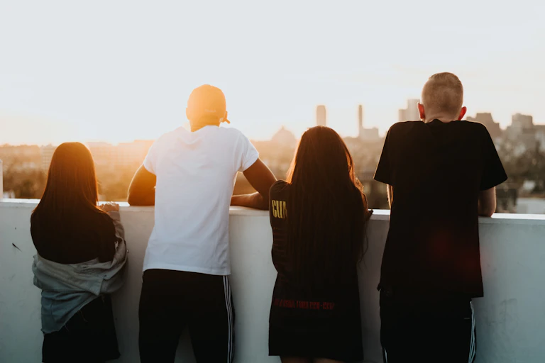 Four young people viewed from behind as they look out over a city.