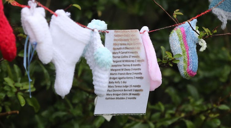 Baby clothes and a list of names hung on a washing line.