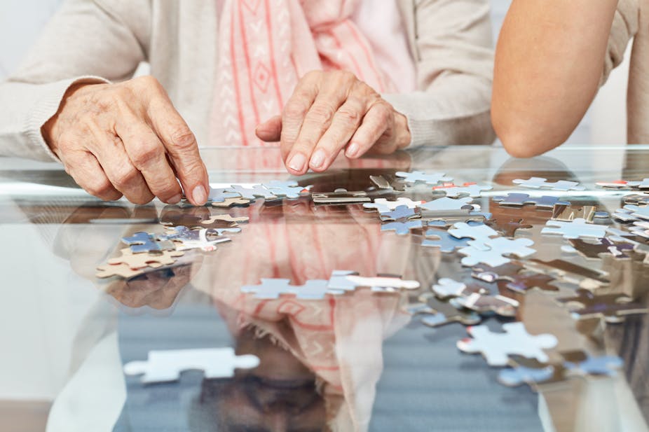 Image of the hands of seniors playing a jigsaw puzzle.