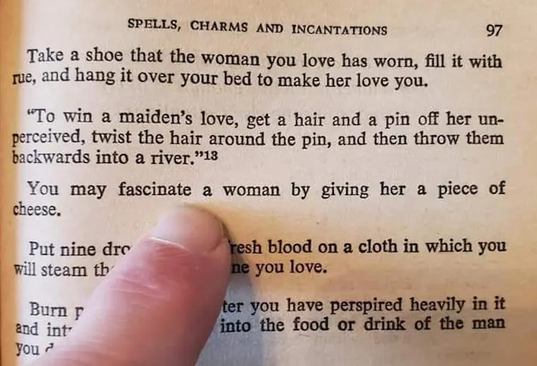 A finger points at a line from a book of spells.